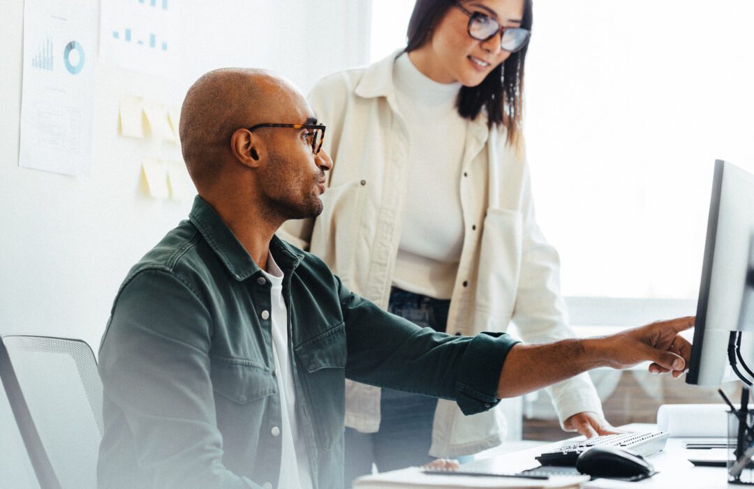 Software developer using a computer and having a discussion with his manager