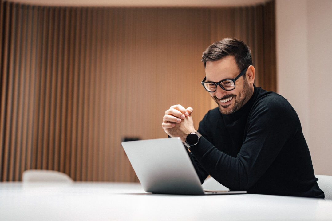 Joyful adult man, attending a meeting online on his macbook.
