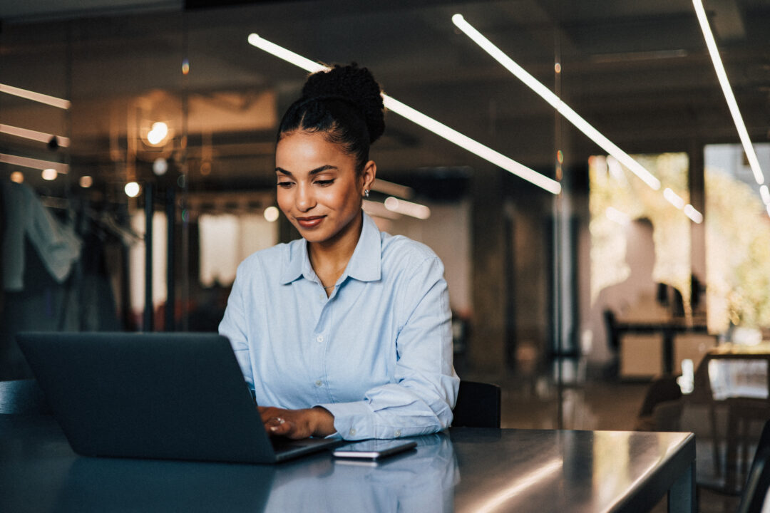 An adult African businesswoman working at the office using a lap